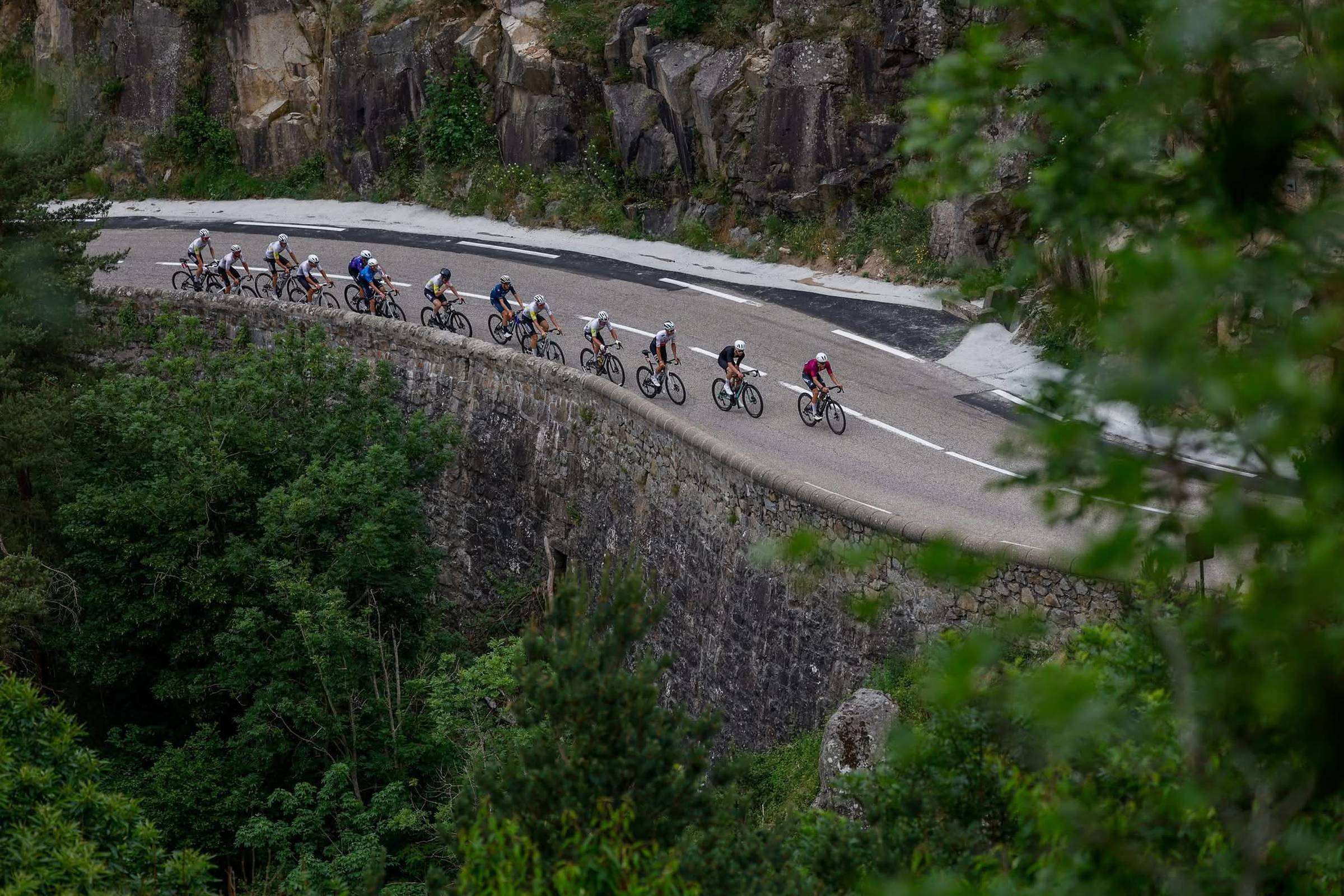 A group of cyclists riding through a mountain bend